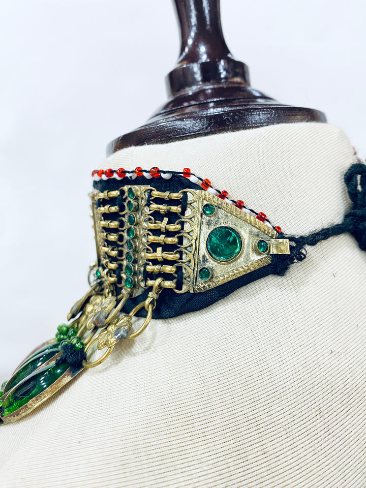 Decorative jewellery with green gemstones and gold accents on a mannequin.
