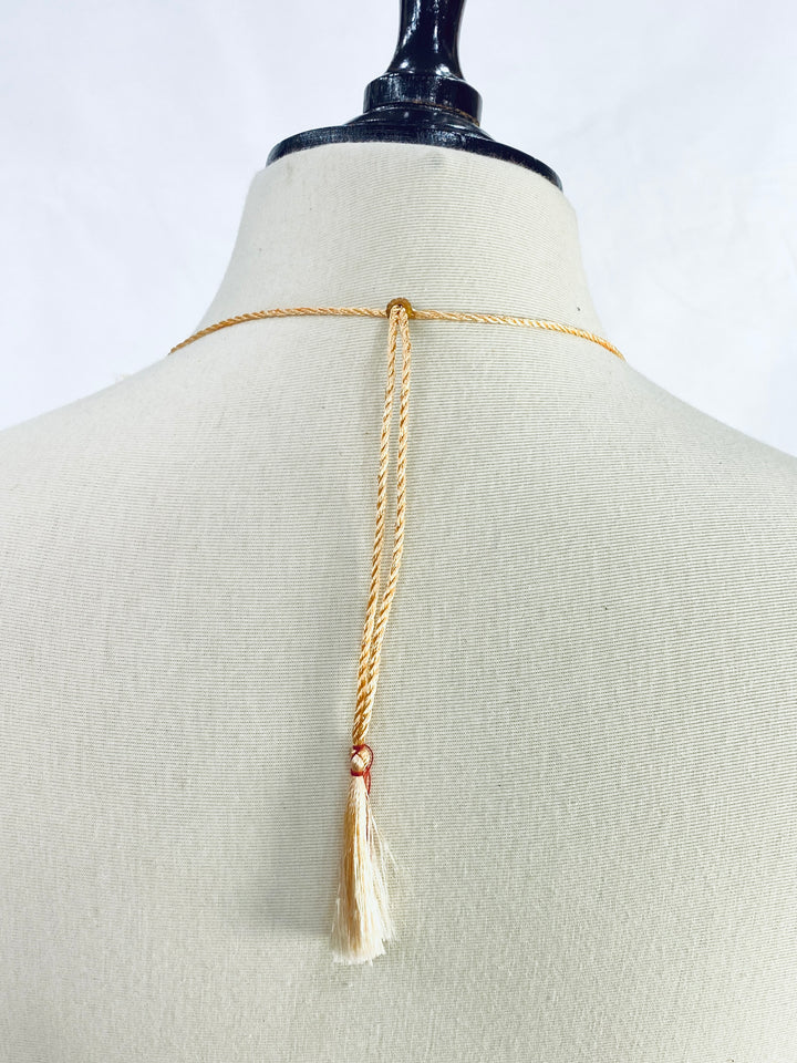 Gold body chain on a mannequin with a plain background
