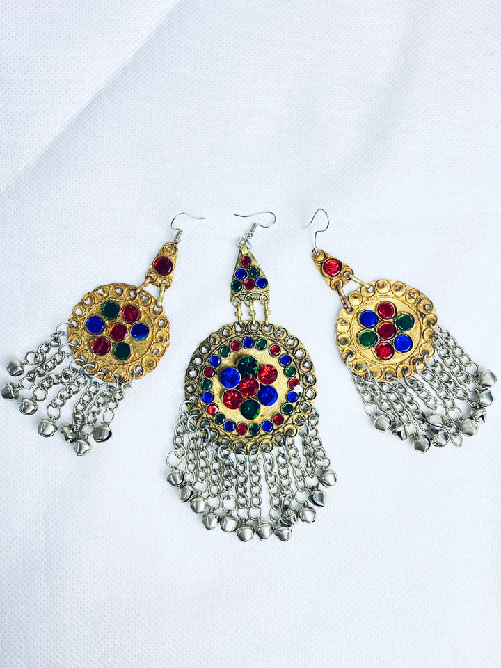 Ornate earrings with colorful gemstones and dangling elements on a white background
