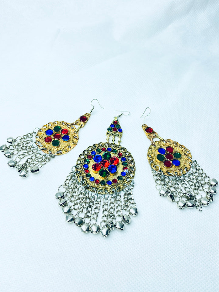 Ornate earrings with colorful gemstones and dangling beads on a white background