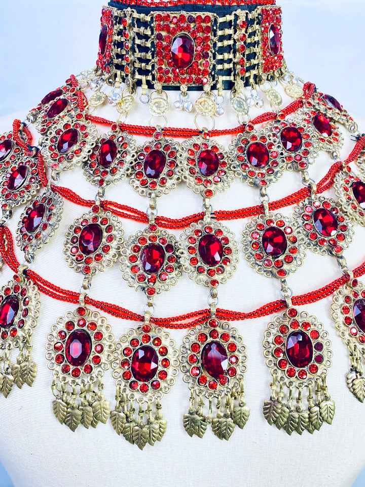 Ornate necklace with red gemstones and gold accents on a white background