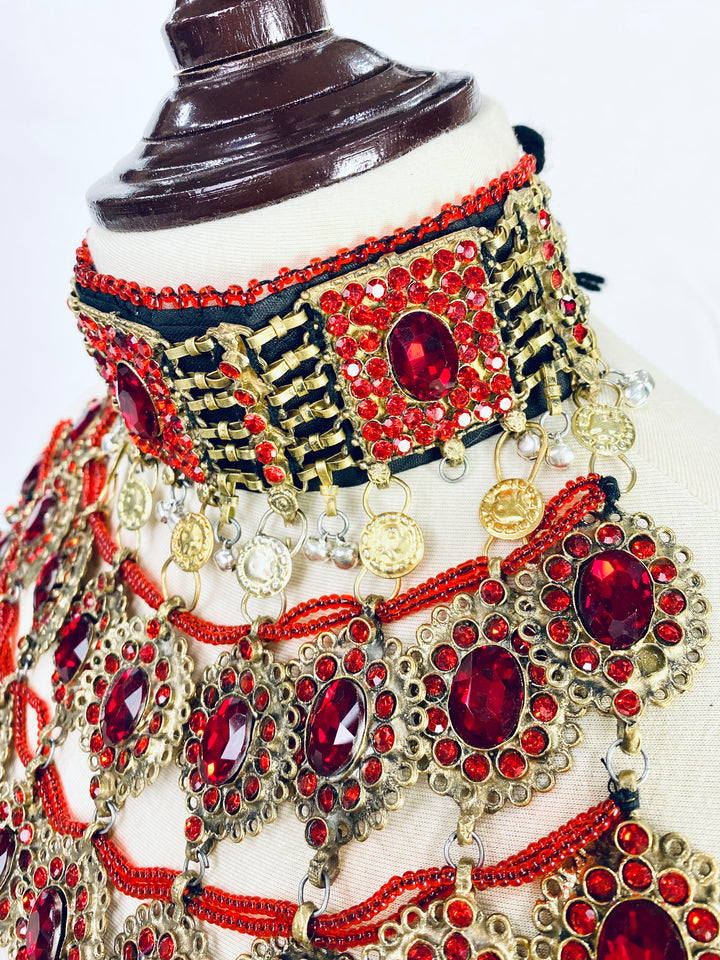 Decorative headpiece with red and gold embellishments on a mannequin.
