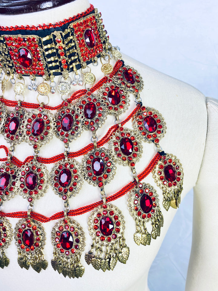 Ornate jewelry with red gemstones and gold accents on a mannequin.