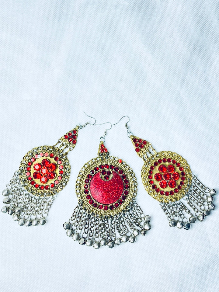 Decorative earrings with red and gold center and silver fringe on a light gray background