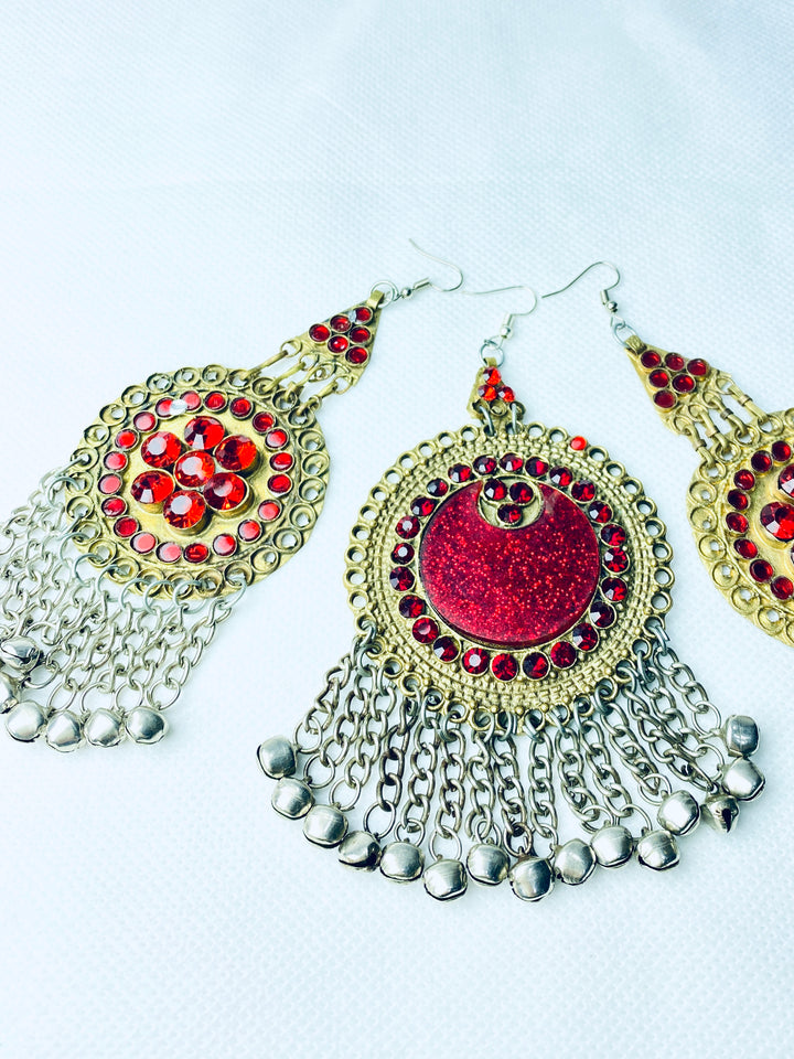 Ornate earrings with red gemstones and silver chains on a white background
