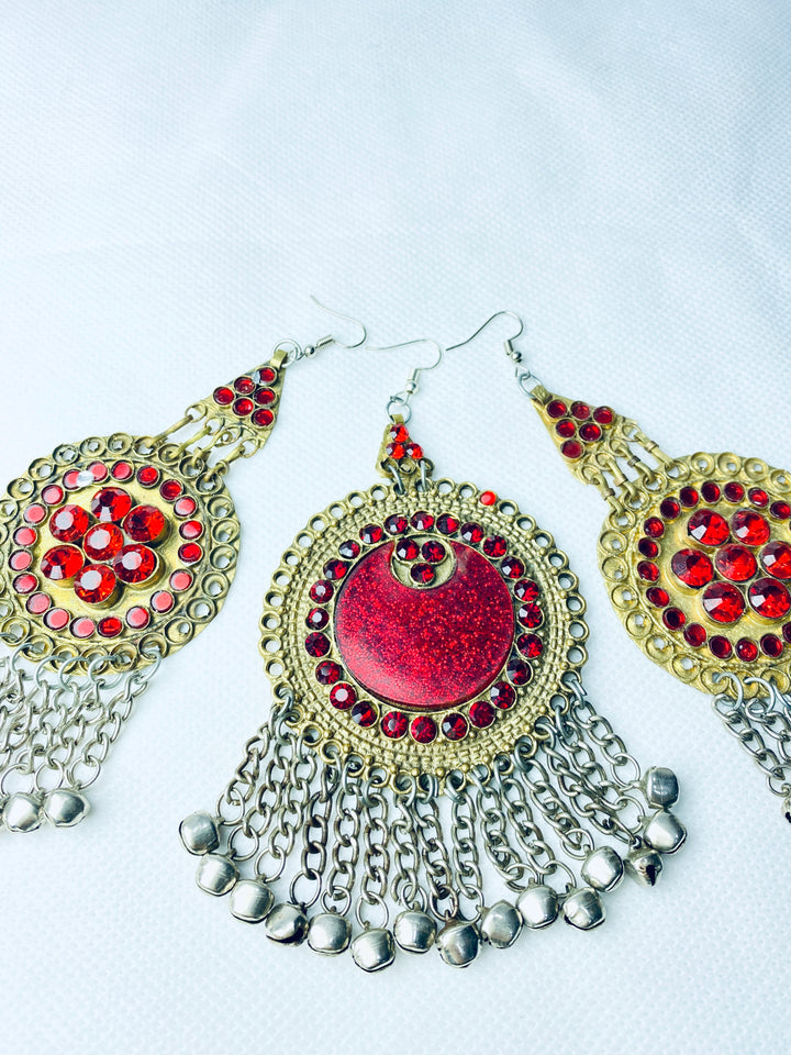 Ornate earrings with red gemstones and silver chains on a white background