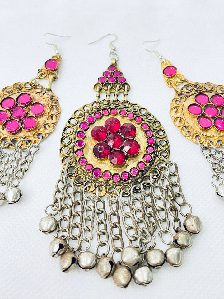 Ornate earrings with pink gemstones and chain details on a white background
