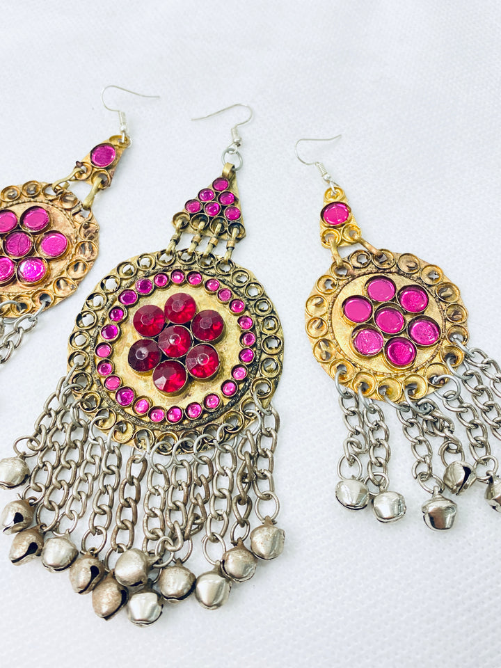Pair of ornate earrings with pink gemstones and chain fringes on a white background