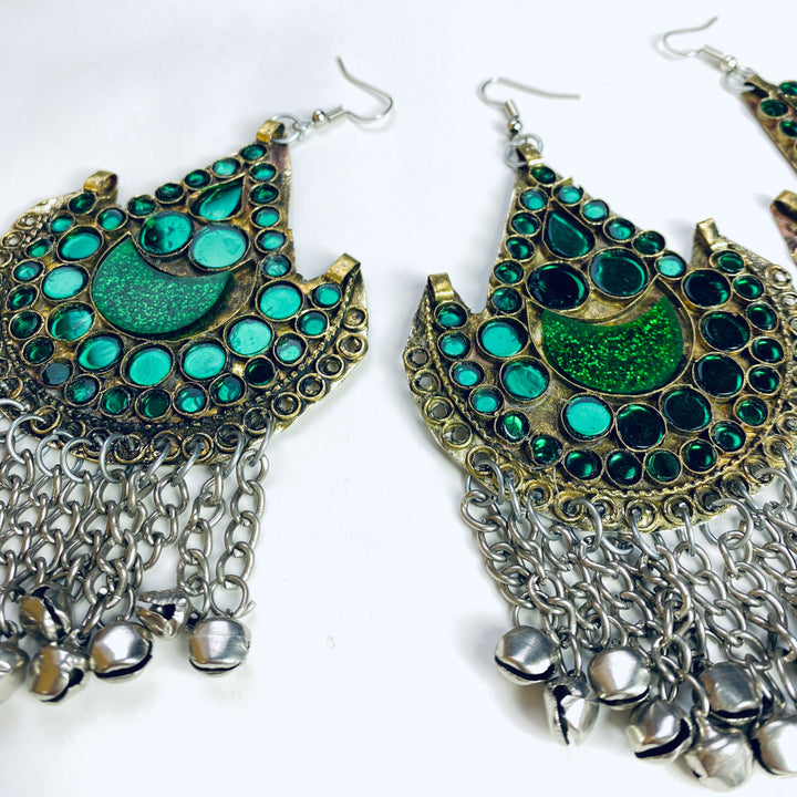 Ornate earrings with green gemstones and silver chains on a white background