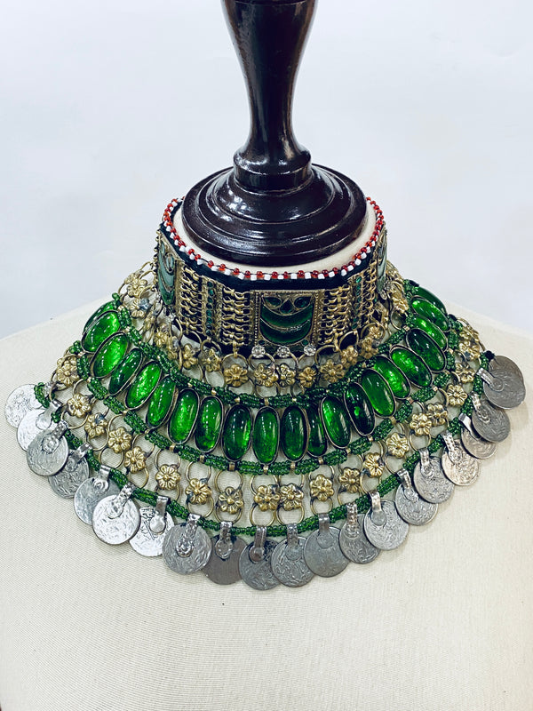 Decorative jewelry piece with green stones and gold accents on a white background