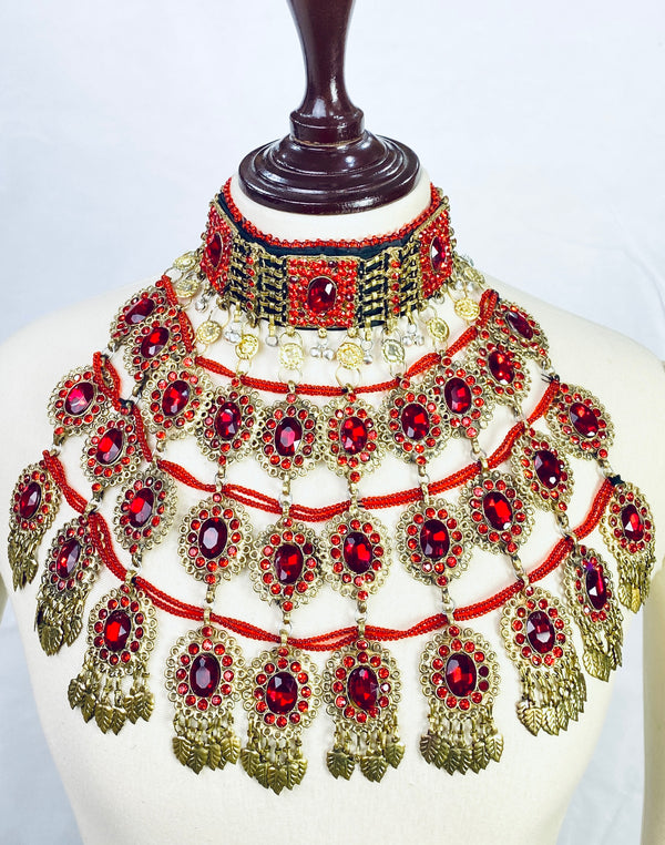 Ornate necklace with red and gold details on a mannequin against a white background